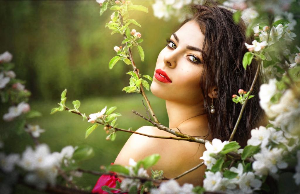 美丽的年轻女孩在一棵开花的苹果树的分支
