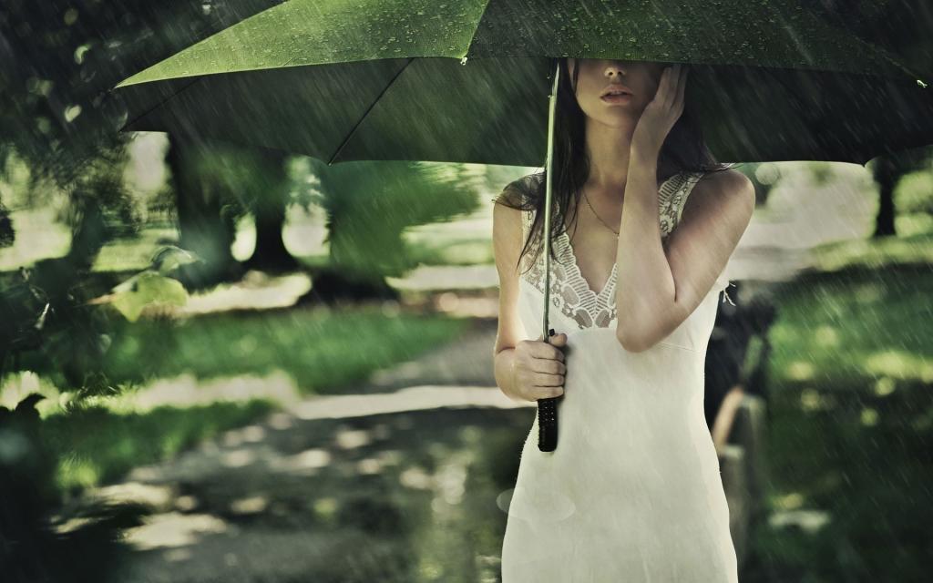 在一把绿伞下的女孩在雨中
