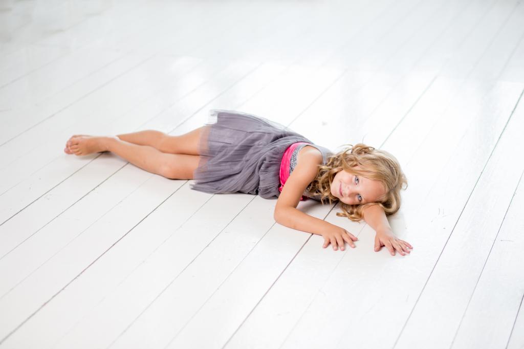 一件灰色的连衣裙的小女孩模型躺在木地板上