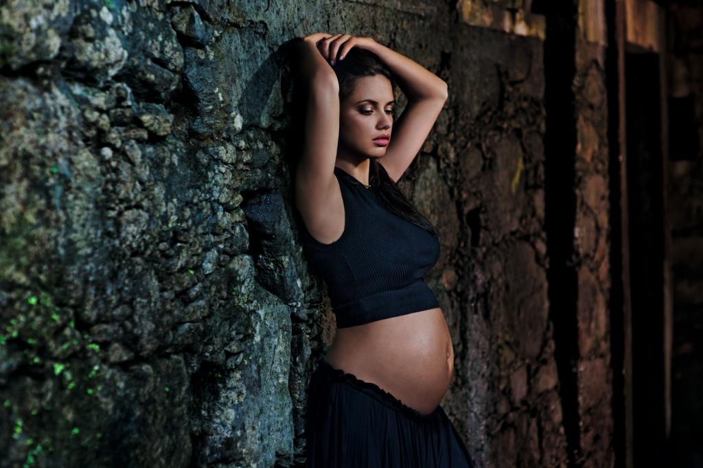 黑色礼服的怀孕的女孩在墙壁