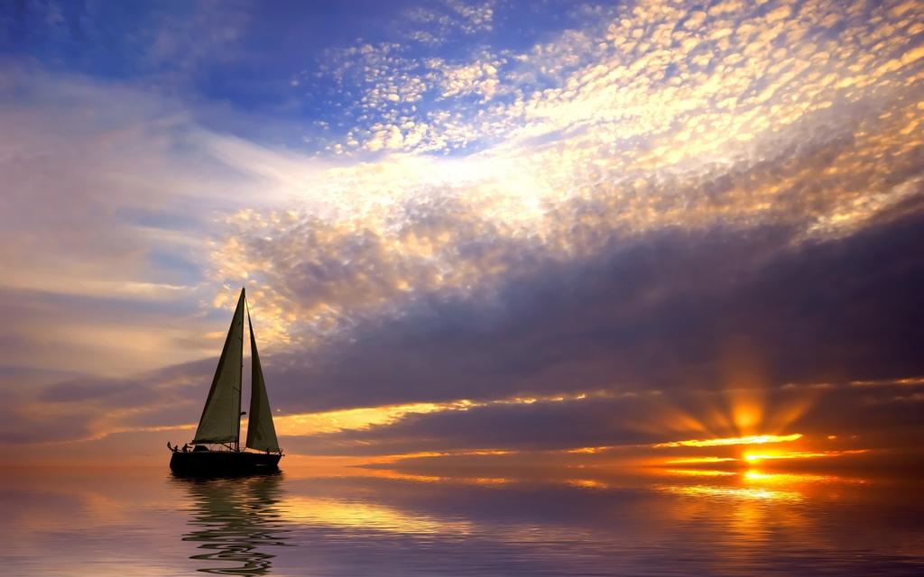 帆船在日落时平静的海面