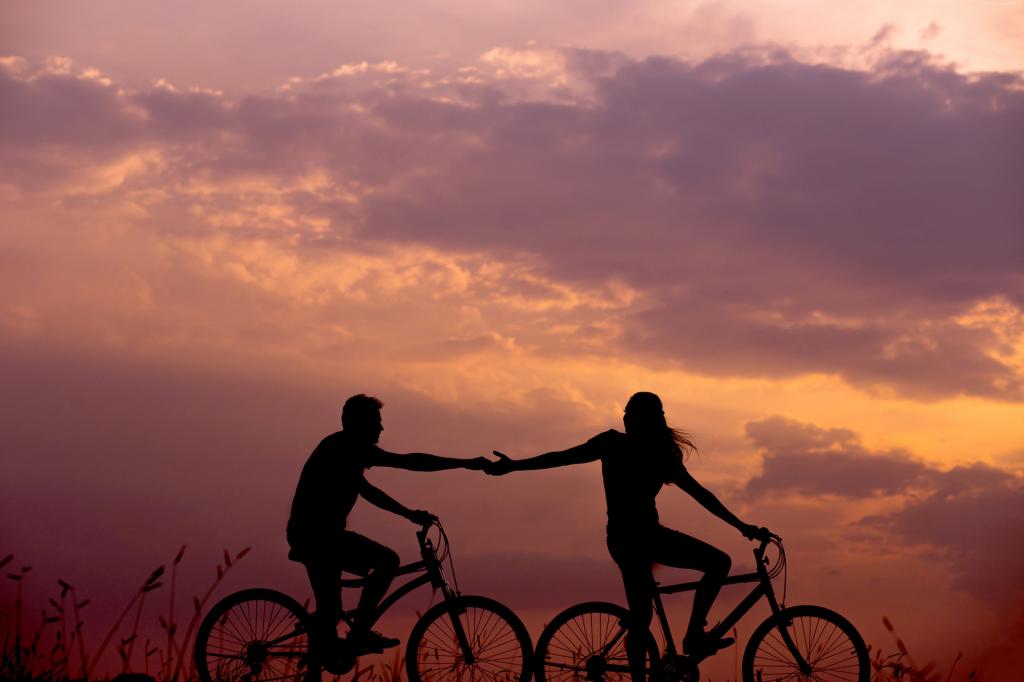 骑自行车的恩爱夫妻在日落时骑