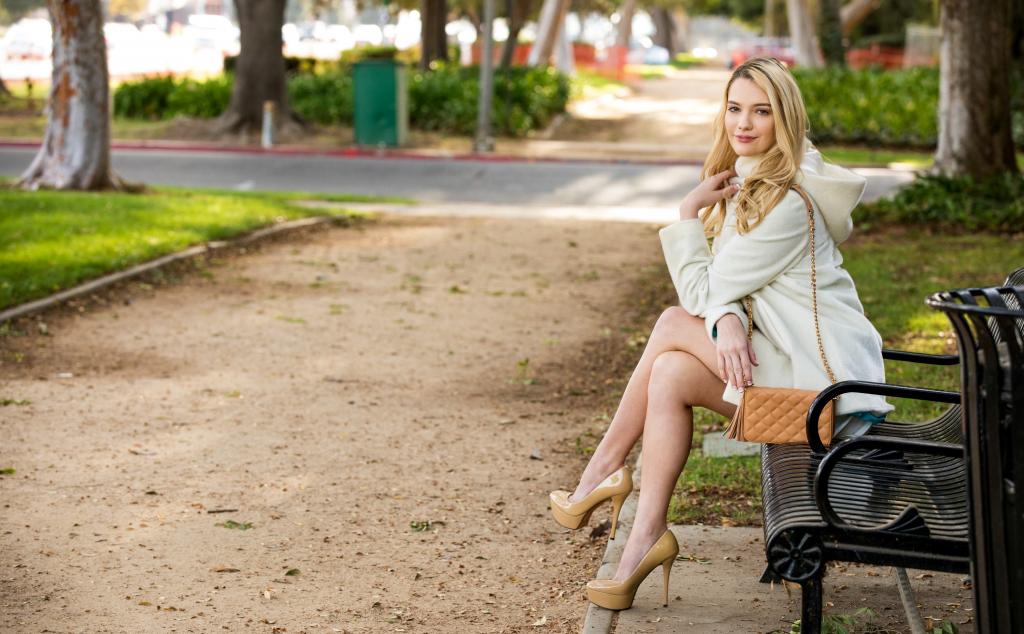 美丽的女孩时装模特肯纳詹姆斯坐在公园的长椅上