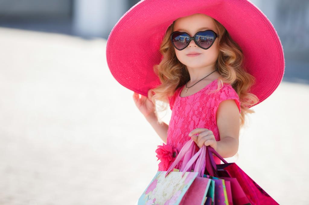 时尚的小女孩在一个大粉红色的帽子